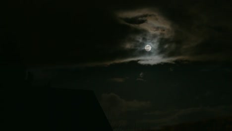 cloudy dark sky with a shiny full moon in east berlin, germany