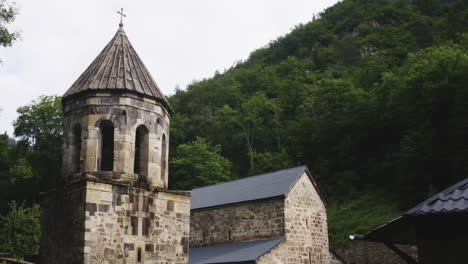 bell tower and church of mtsvane monastery below wooded hill, georgia