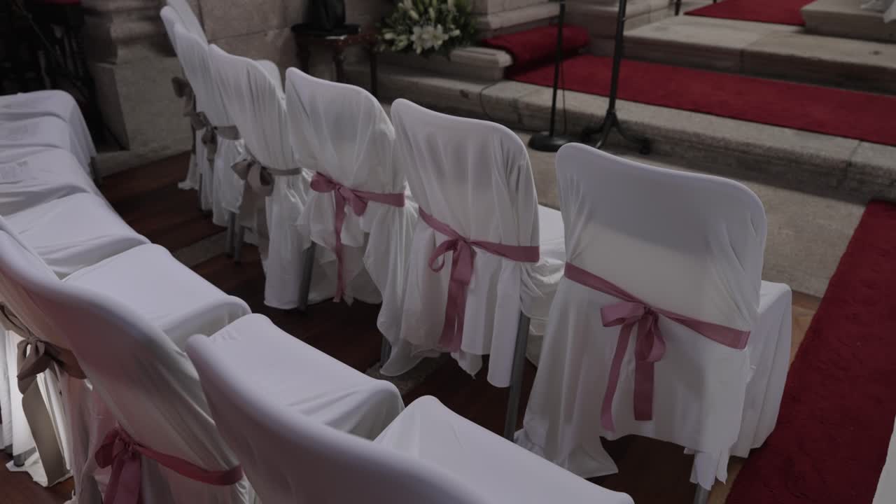 elegantly tied wedding chairs lined up near church altar on red carpet