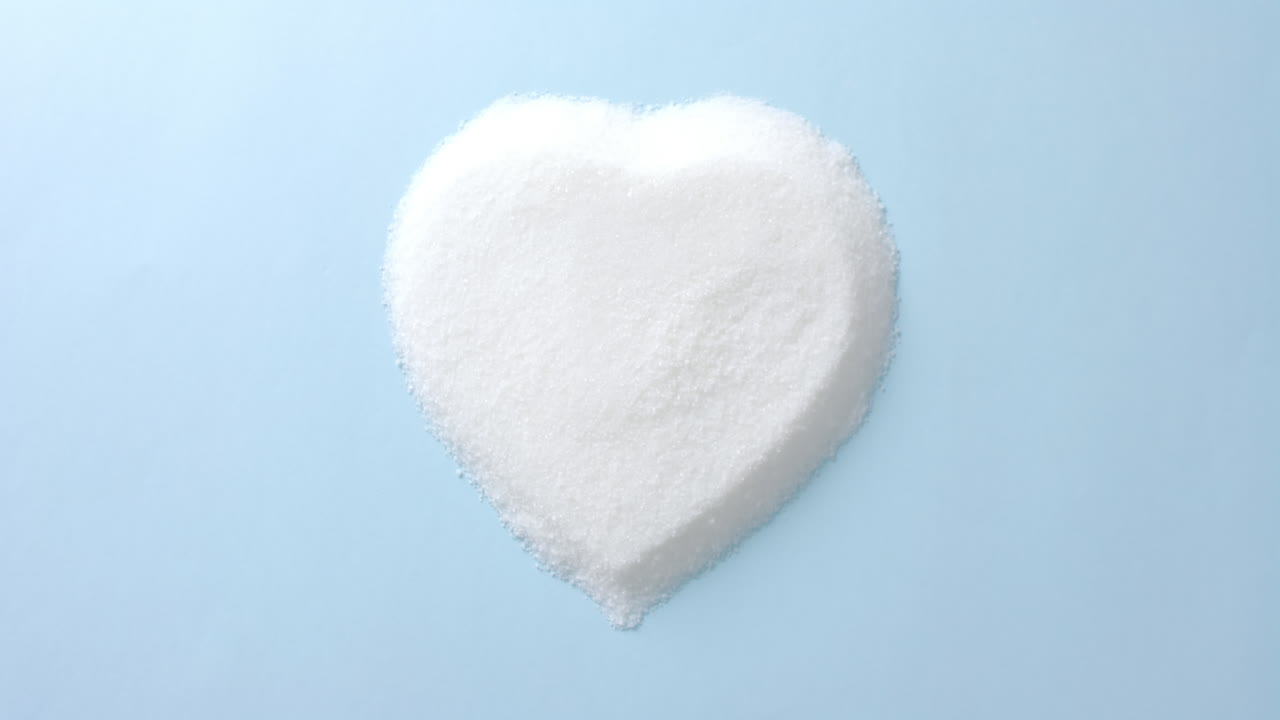 cerrado de azúcar en forma de corazón en fondo azul con espacio de copia, cámara lenta.