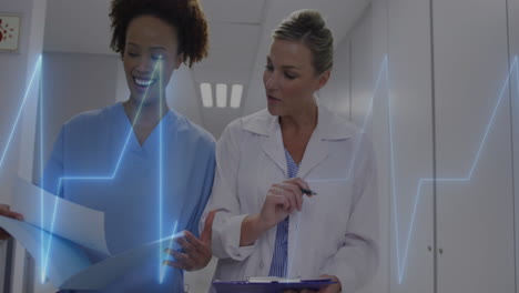 animation of heart rate monitor over diverse female doctor and health worker discussing at hospital