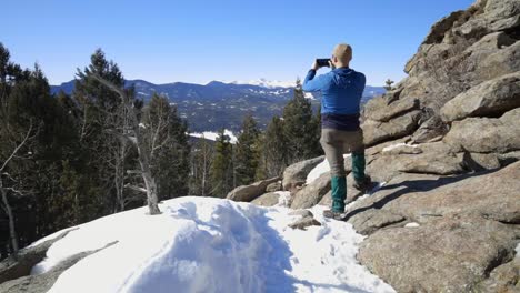 excursionista tomando una foto del monte evans en la distancia durante una caminata de invierno en colorado