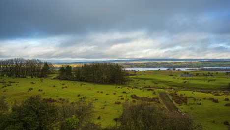 Timelapse-of-rural-nature-farmland-landscape-with-field-trees-and-lake-farmhouse-in-distance-during-sunny-cloudy-day-viewed-from-Carrowkeel-in-county-Sligo-in-Ireland