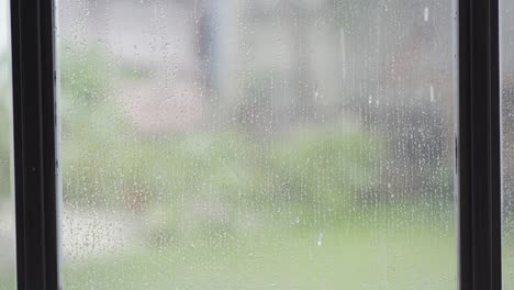 high quality 4k video of the falling rain in the falling sky, seen from the glass window slowly at close range, seasonal daytime rain.