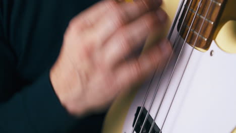 funky bassist in black pullover plays white guitar closeup