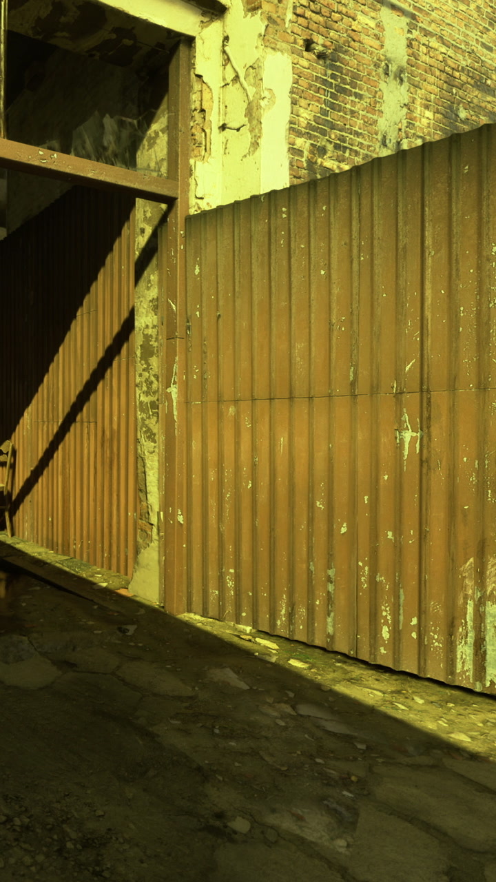 Rustic structure with weathered walls and a large wooden door in a courtyard