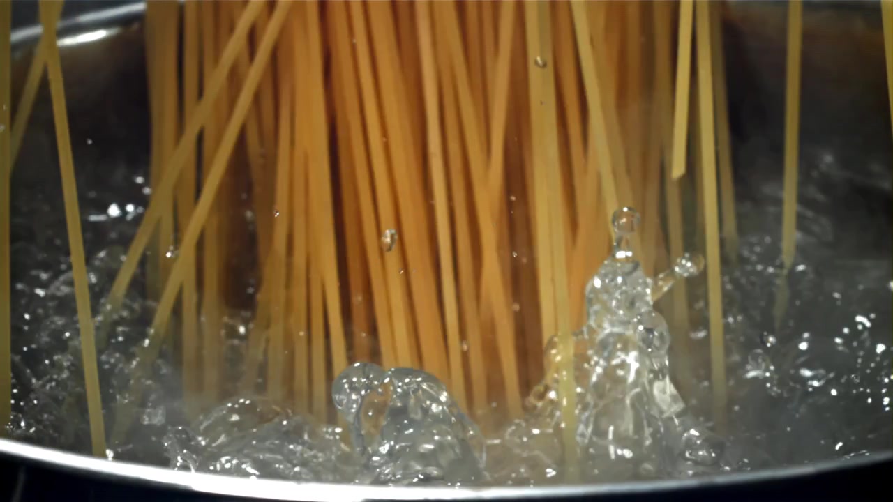 Movimento rallentato di spaghetti che cadono nell'acqua bollente