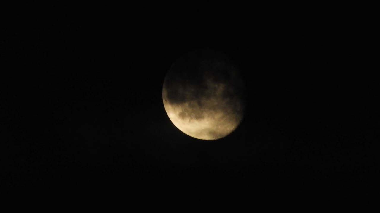 Moon at night with cloud real time. 4k video moon in the black sky.  Clouds passing by moon at night. night sky with cloudy weather