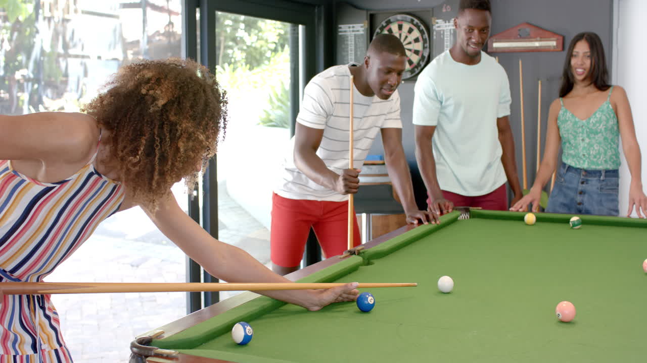 Young African American men and biracial women enjoy a game of pool