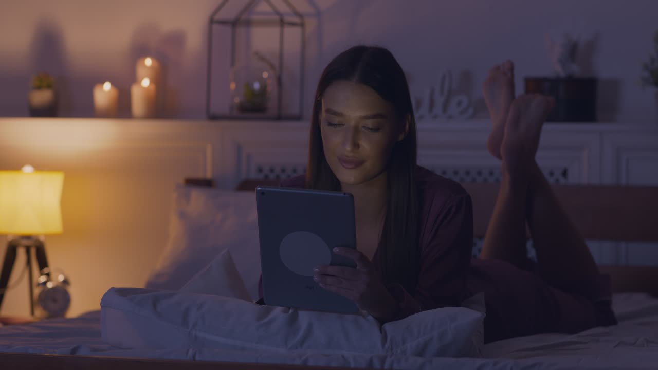 Woman relaxing in bed with tablet at night