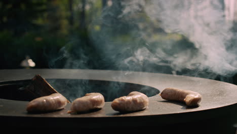 unrecognized man putting sausages on bbq grill outdoors. chef cooking sausages