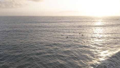 Tres-Surfistas-En-Aguas-Frías-De-Islandia-Durante-La-Espera-Del-Alba-En-Fila,-Antena