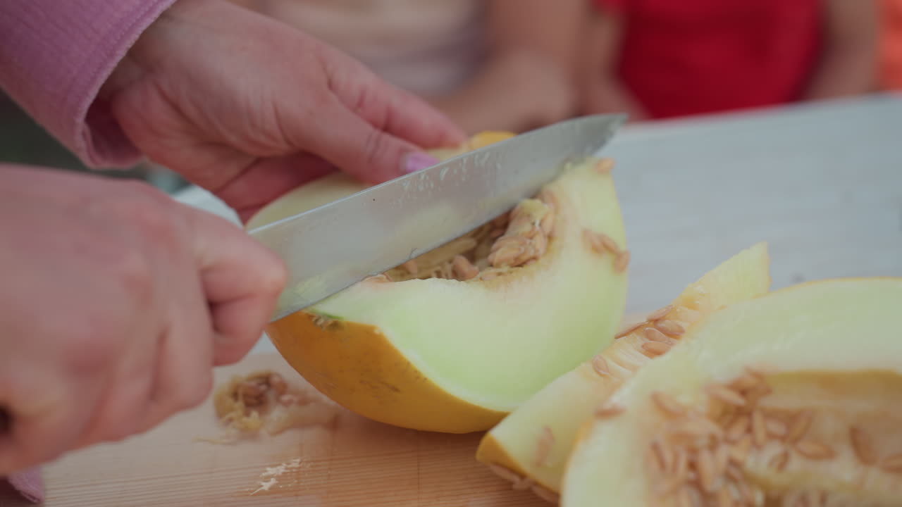 Woman Slices Melon For Picnic, Casual Outdoor Gathering With Juicy Melon Pieces And Children, Relaxed Summer Setting Featuring Woman Preparing Juicy Melon Wedges For Sharing Among Children
