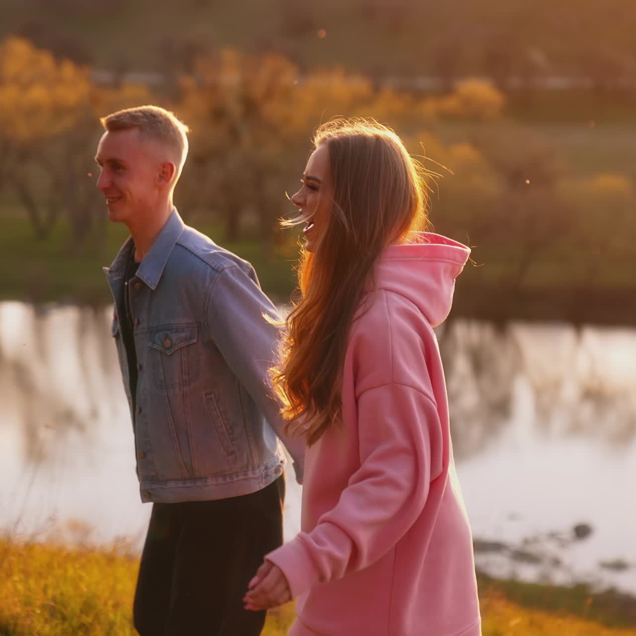 Happy girl and boyfriend walking in the evening. Young couple spending time together on beautiful nature background. Slow motion