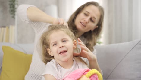 The-mother-is-combing-the-blonde-girl's-hair.