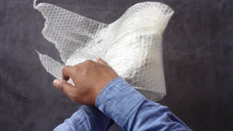 a man's hands packing an item in bubble wrap