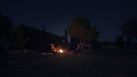 timelapse shows a group of people gathered around a campfire with the sparkling night sky above