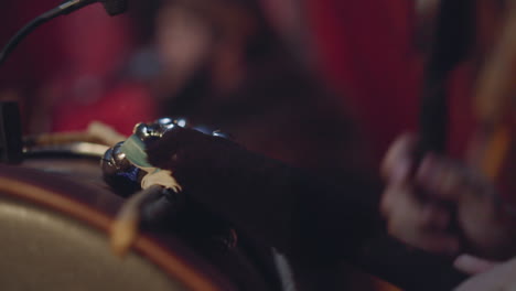 musician taps drums with small bells playing folk music