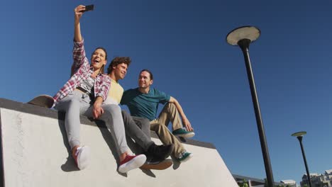 Happy-caucasian-woman-and-two-male-friends-taking-selfie