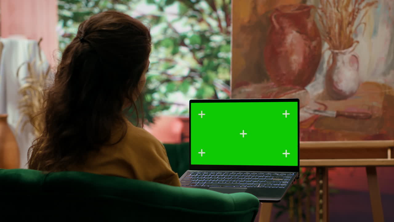 Woman using laptop with green screen at home studio