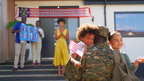 los niños abrazan a su padre como una familia multigeneracional que da la bienvenida al padre del ejército a casa de licencia con un estandarte