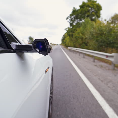 white car on the highway. close-up part of audi car moving on the road at daytime. button on the mirror of the car blinking while electic car is driving.