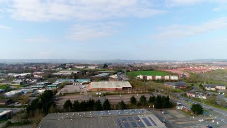 Sideways-tracking-aerial-of-Sowton-industrial-estate,-Exeter,-UK,-looking-across-Honiton-Road-and-in-the-distance-the-city-centre