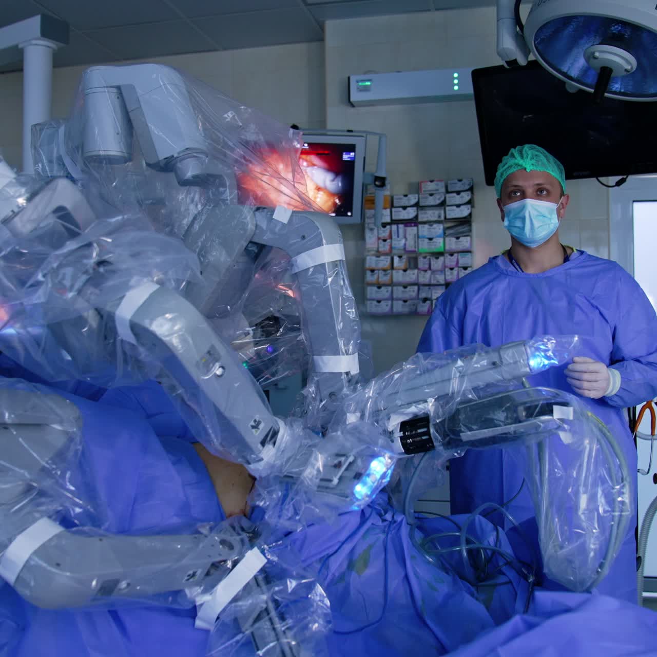 Focused male surgeon looking attentively on the screen in front of him. Doctor monitoring the process of laparoscopy conducted by Da Vinci robot