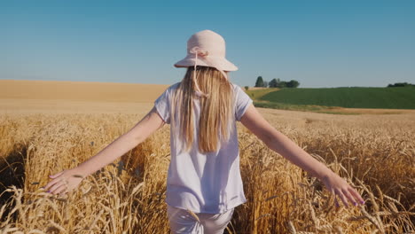 a child in a hat walks along the path in wheat