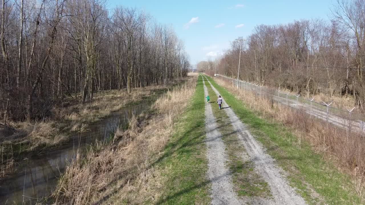 Two Kids Walking On The Trail At The Park In Monroe, Michigan On A Sunny Day - Drone Shot