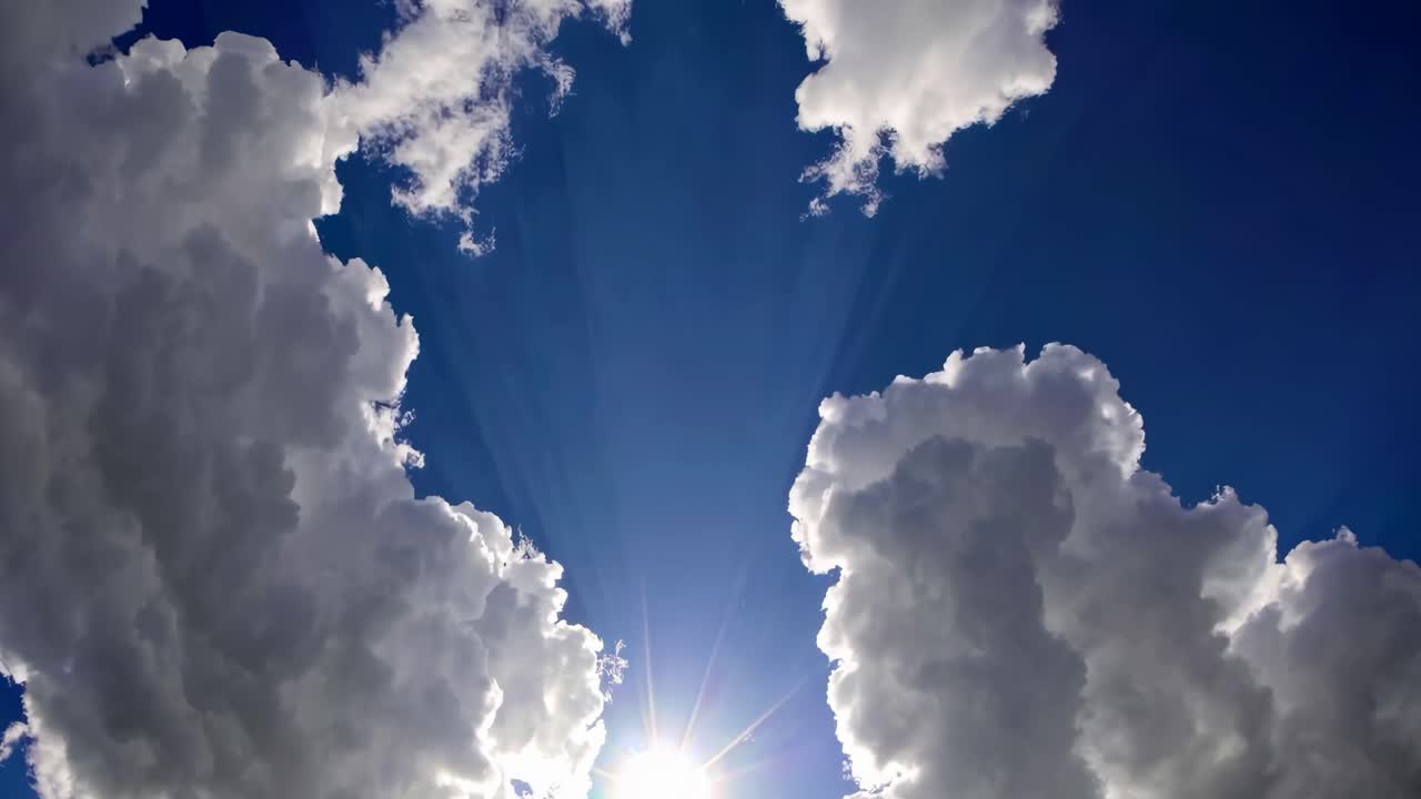 A video captures a low-angle view of fluffy white clouds against a deep blue sky, creating a serene