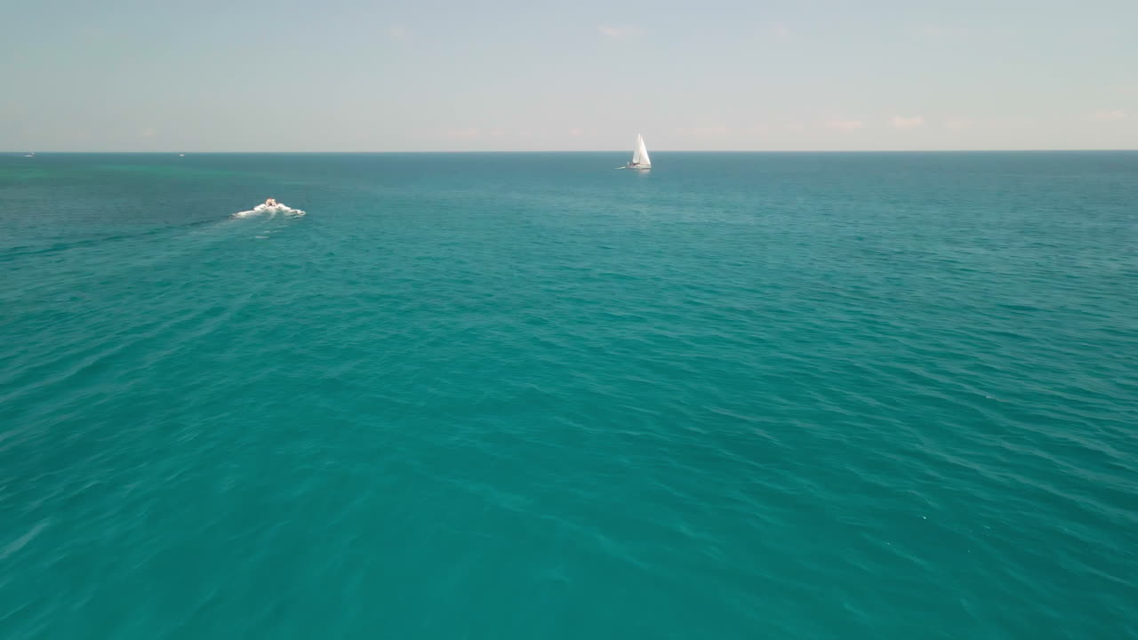 lancha rápida y velero navegando a través del océano azul en cerdeña, italia en verano