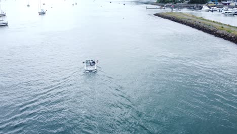 Following-motor-boat-vessel-aerial-view-navigating-quiet-river-Conwy-harbour-marina-seaside-town