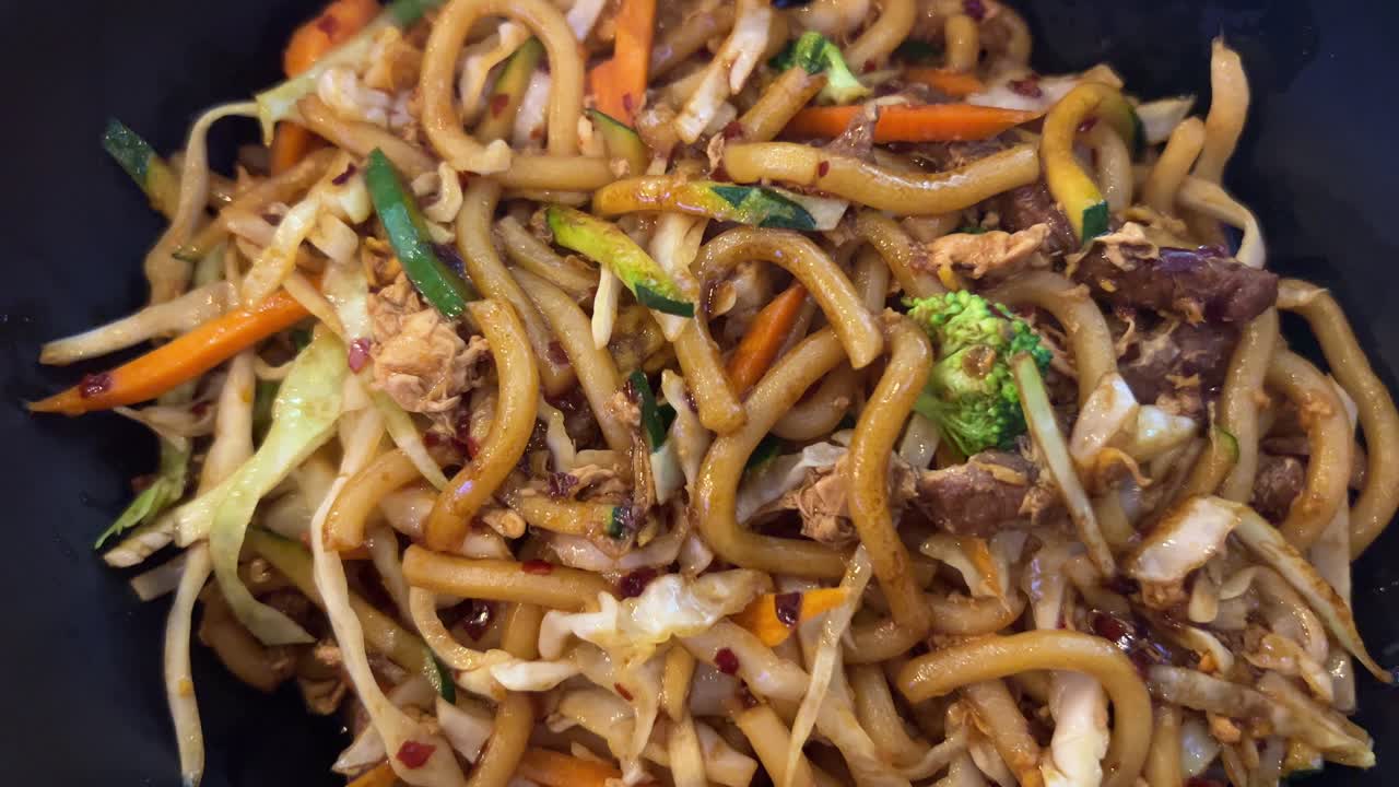 deliciosos fideos udon picantes de pollo y ternera con verduras, fideos fritos al wok, cocina asiática, tiro de 4k