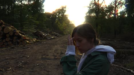 mujer afectada por la deforestación, mirando una pila de madera en el bosque