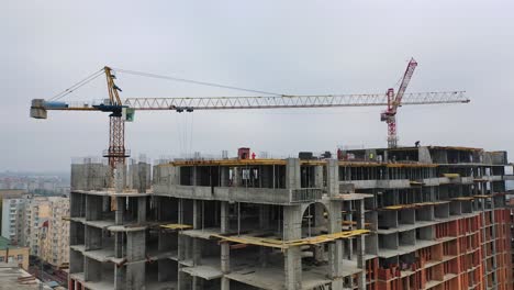 process of construction high-rise building. labor workers on a big construction site on the background of working crane in the city. slow motion. camera moves top down.