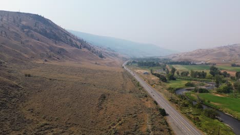 scenic aerial view over hillside mound, cariboo highway, and river in bc, canada