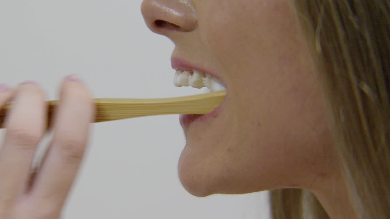 una mujer cepillándose los dientes, girando hacia la cámara