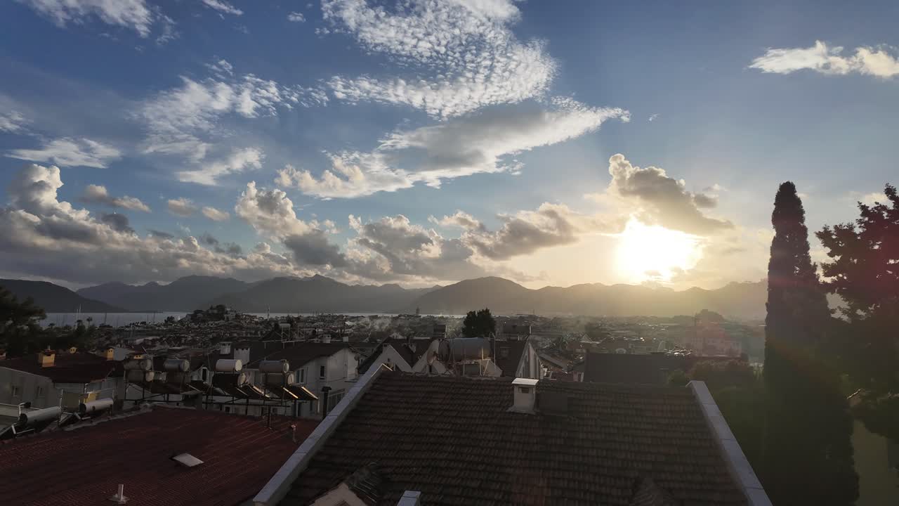 Time lapse of white cumulus clouds move in the blue sky during sunset over Marmaris Bay and town.