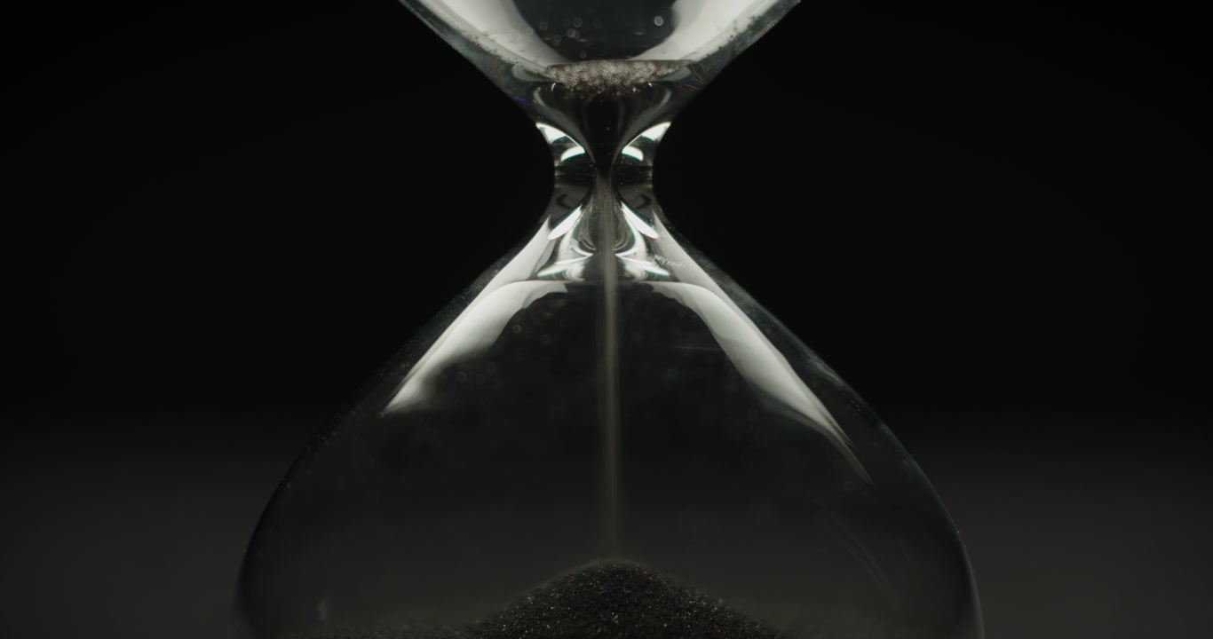 Black sand pouring inside sand clock