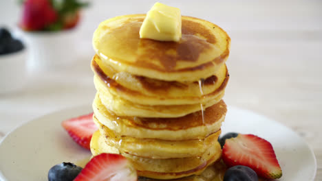 pancake with butter, strawberries, blueberries and honey