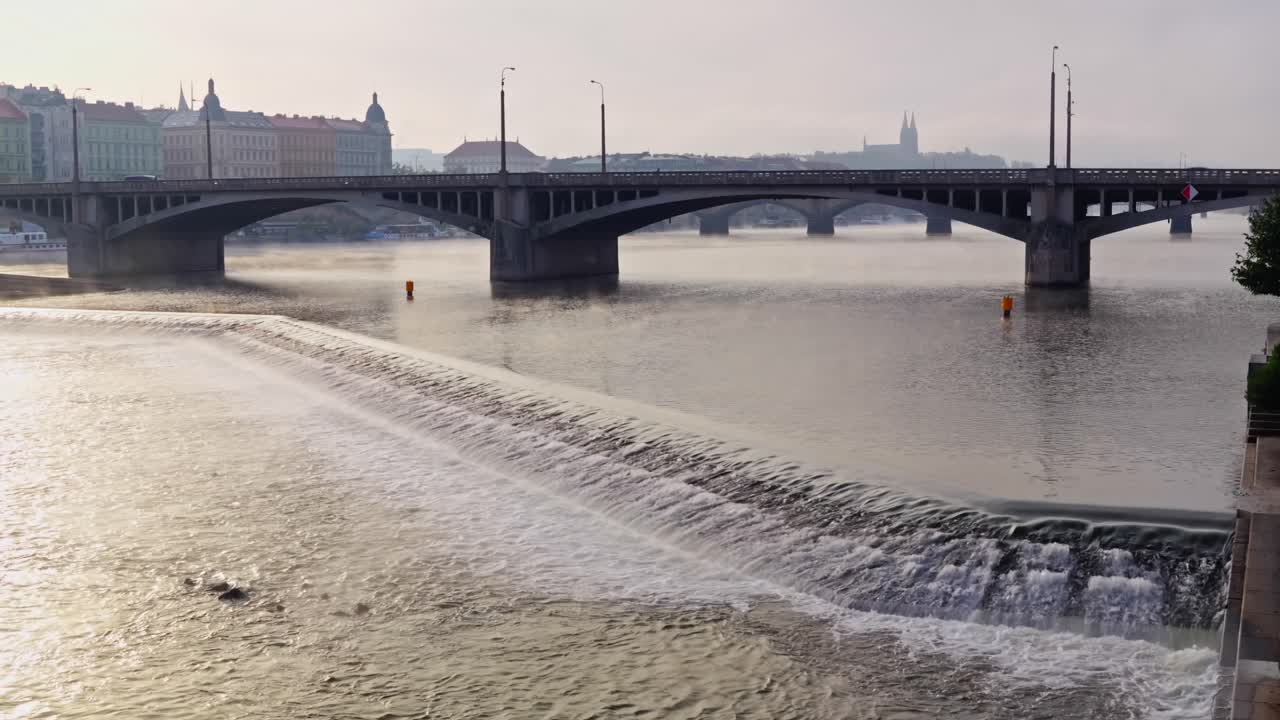 Autumn morning sunlight falls upon Vltava river cascading weir Prague