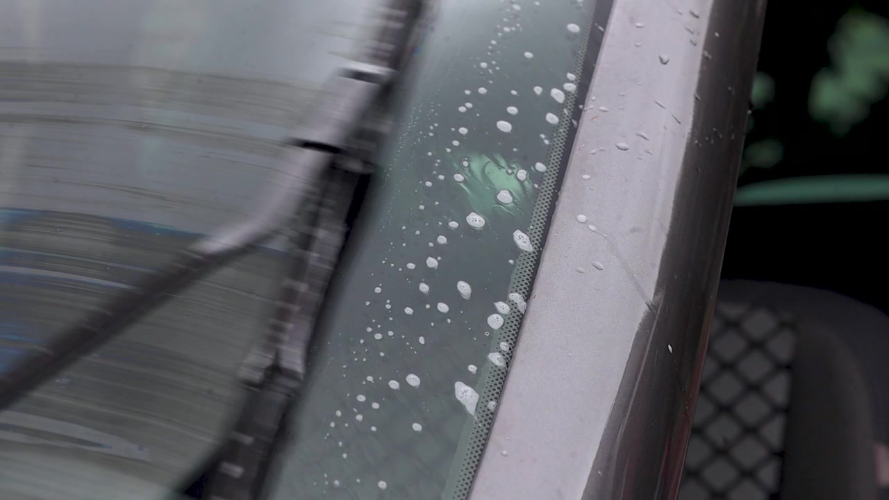 Video close up of windshield wipers moving washer fluid away.