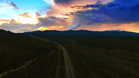 speedway with multiple cars riding by in the deserted land. evening view of death valley from top.