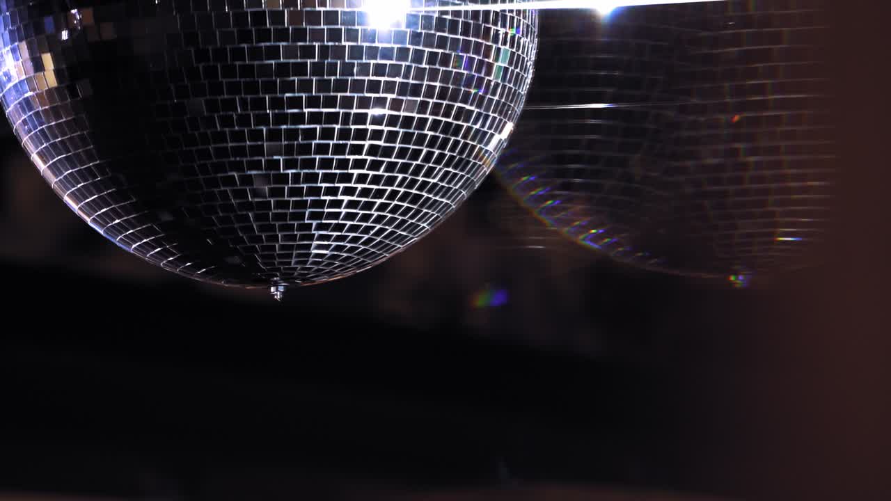 Disco ball is spinning. Round mirror ball reflecting real club lights and lasers. Evening party. Reflection of light. Lighting device.
