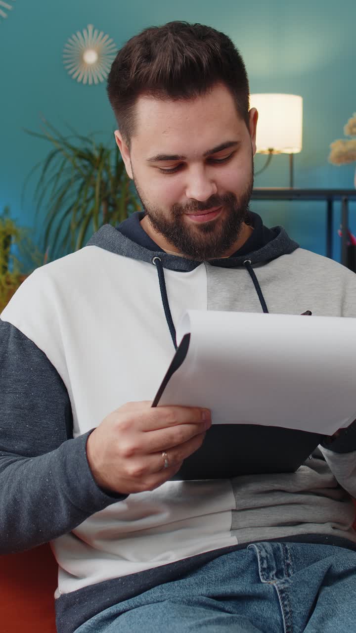 Joven trabajador independiente con documentos desde casa analizando información preparando informes financieros