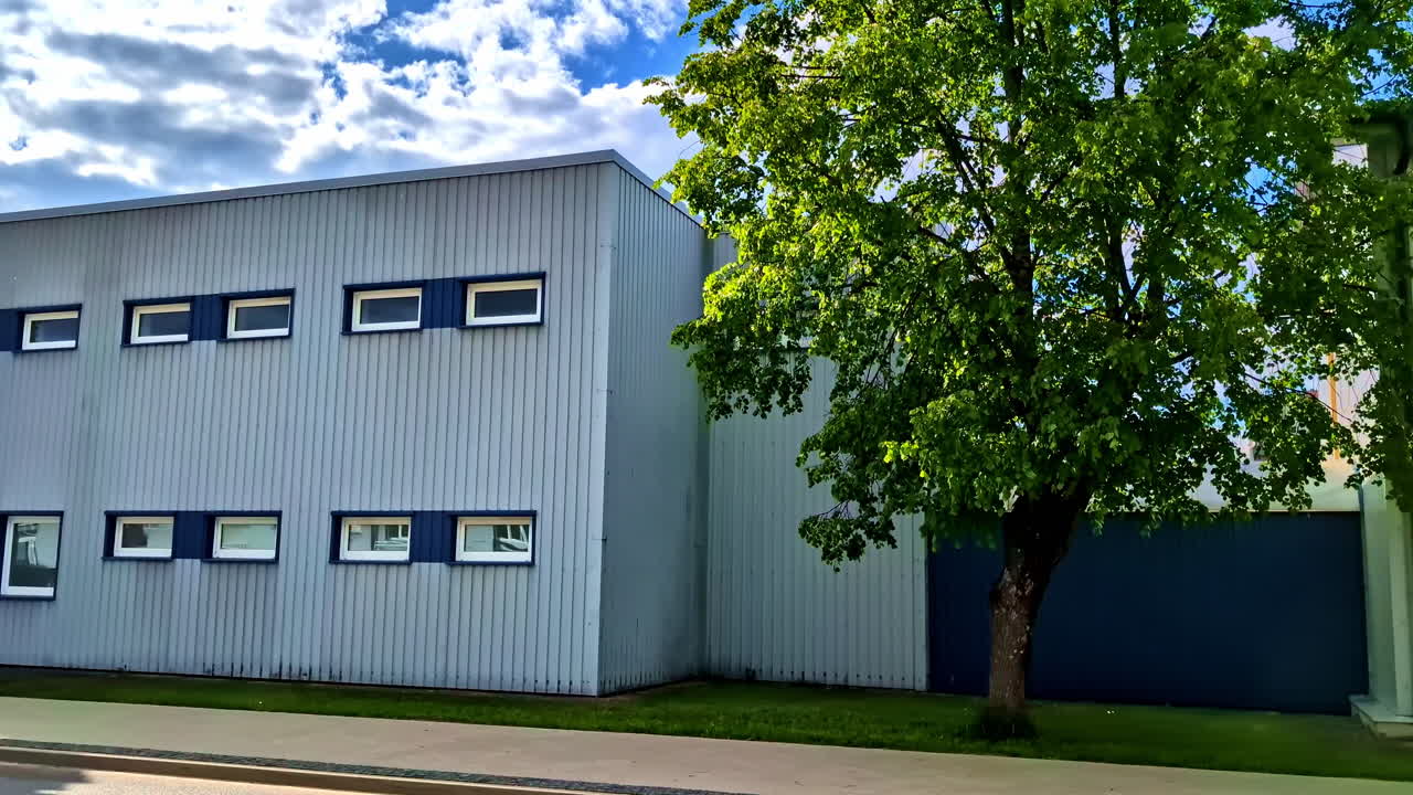Modern Industrial Building With Green Tree and Blue Sky in Background