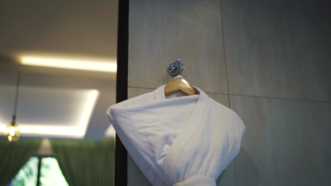 고급스럽고 현대적인 럭셔리 아파트 또는 호텔에서 나무 개 위에 인 우아한 색 수건 로브 - 고급 인테리어 디자인에서 편안함과 스타일의 손길.