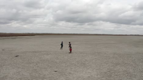 drone round shot of family standing in middle of dry salt lake