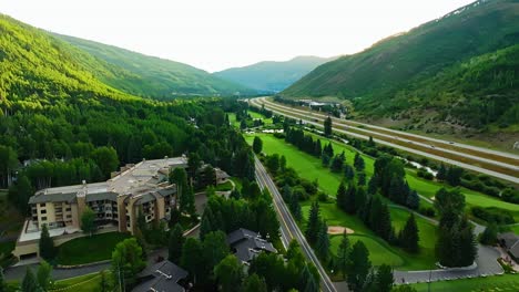 drone flyover of road weaving through bright green hills and alpine terrain near vail colorado